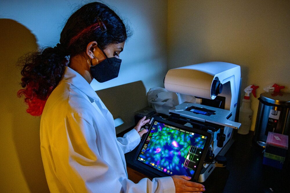 Neha Arun reviews imaging of host-pathogen interactions in a darkly lit room, with her face illuminated by the screen.