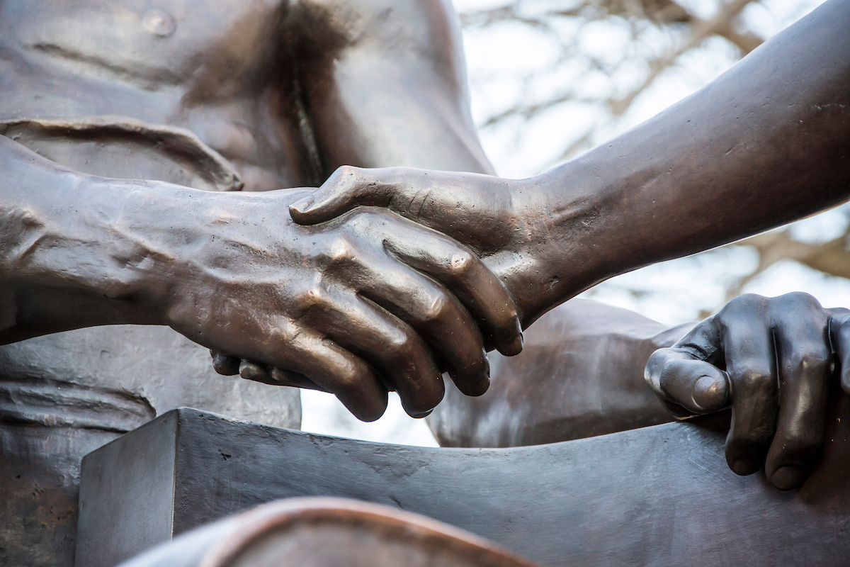 hands shaking on alma mater statue