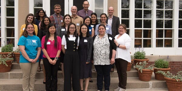 Faculty and students gather at a retreat. They are posed on steps outside in three rows, all smiling.