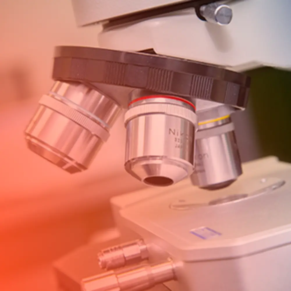 A tight shot of a microscope with a soft orange gradient layer.