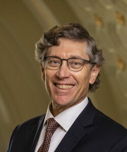 Man with glasses and wearing dark suit and tie